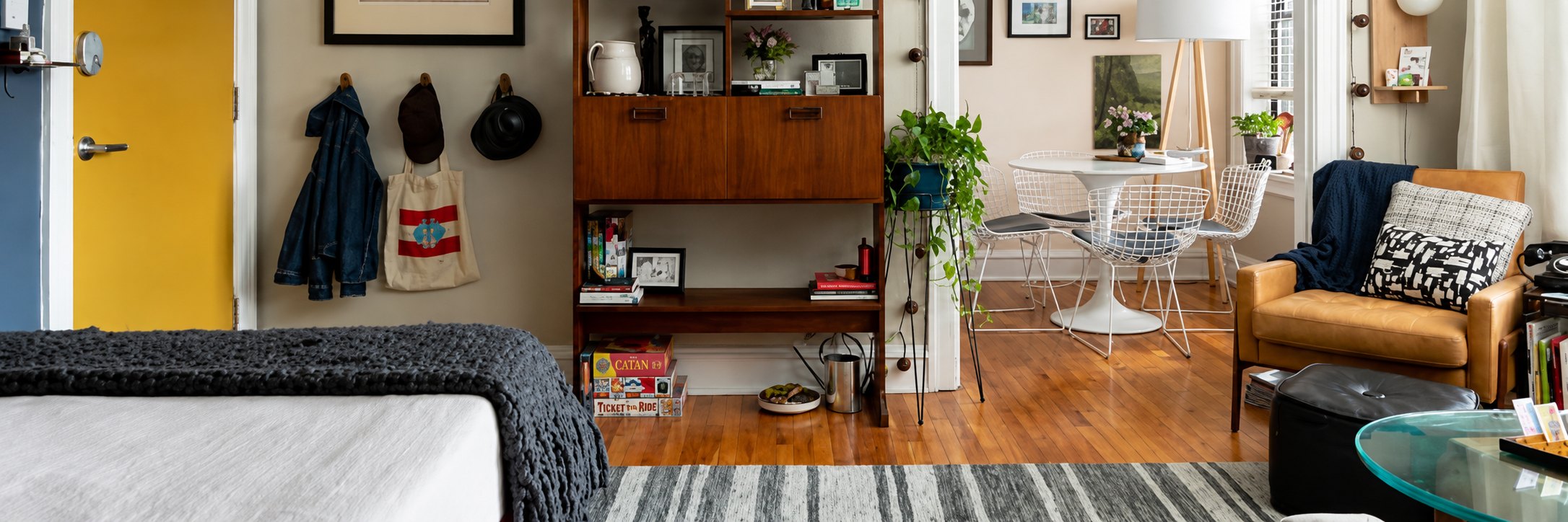  A small apartment interior featuring a bed, a couch, and a small table arranged for cozy living